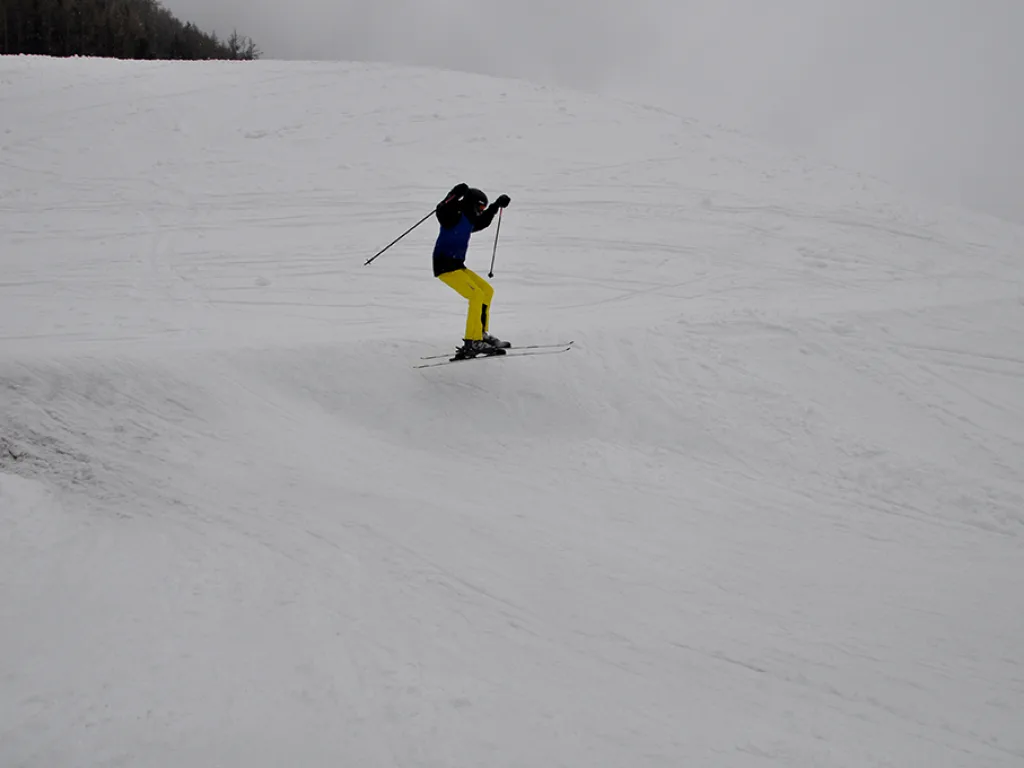 Skifahrer in gelber Hose auf dem weiten Hang.